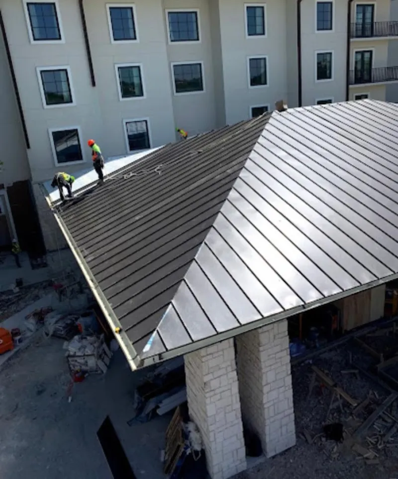 Crew installing standing seam metal roof panels on a commercial project in Claremont
